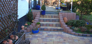 Hofbefestigung mit Betonsteinpflaster in Herbstlaub, sowie Treppenanlage mit Betonpalisaden