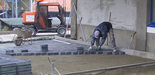 Pflasterarbeiten in Handverlegung, abziehen des Pflasterbettes mit einen Abziehhobel